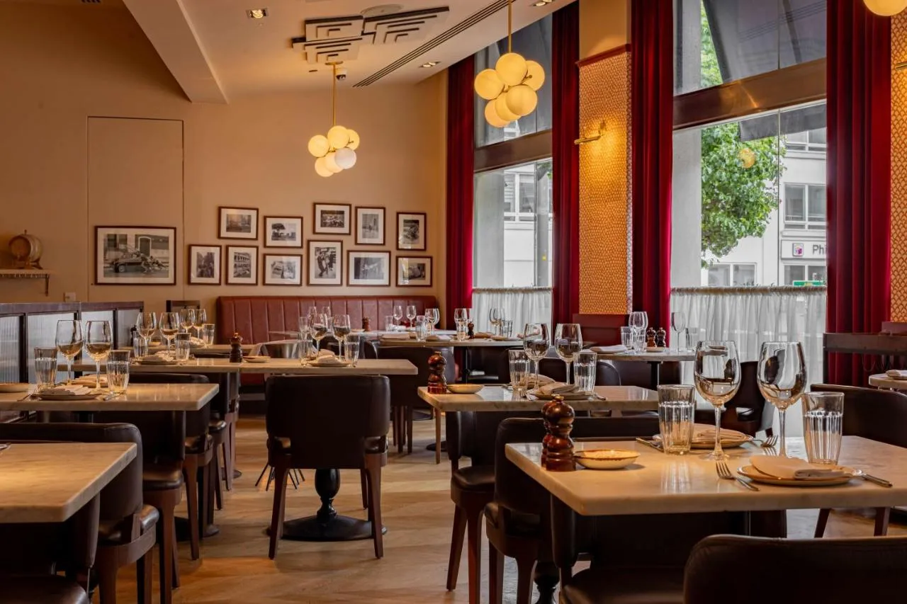 a restaurant with tables and chairs and windows at Park Plaza London Victoria in London